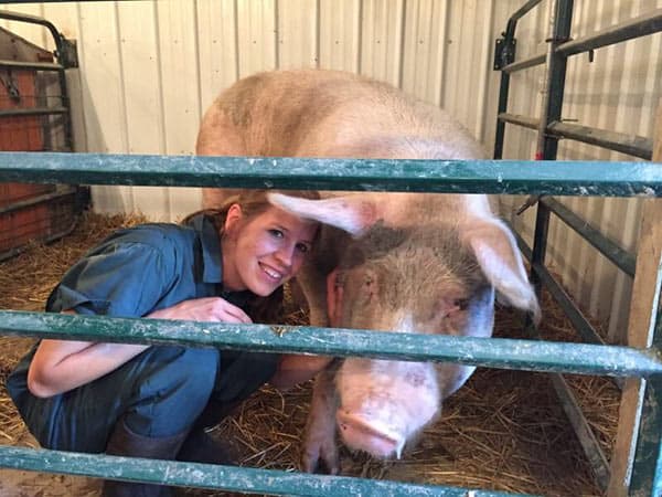 Dr. Emily Thomas posing with pig in a pig farm