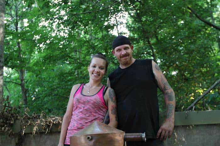 Moonshiners Cast Chico and his wife Cassondra showing tattoo on their arms.